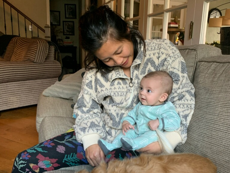 LA doula Priscilla Hsu, an olive skin tone Taiwanese femme with really dope demi-lids and small dimples by the corners of her mouth, is sitting down on a couch and holding a light-skinned baby of boundless potential in the crook of her left arm. The baby is wearing an aqua onesie and gripping the tail fur of a passively disgruntled golden long-haired dachshund (weiner dog).